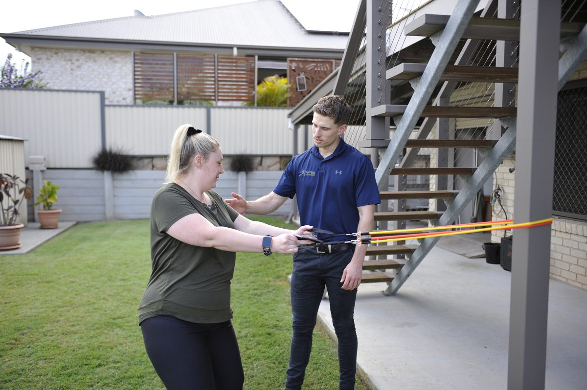 Physiotherapist supporting a client with post-operative rehabilitation at home